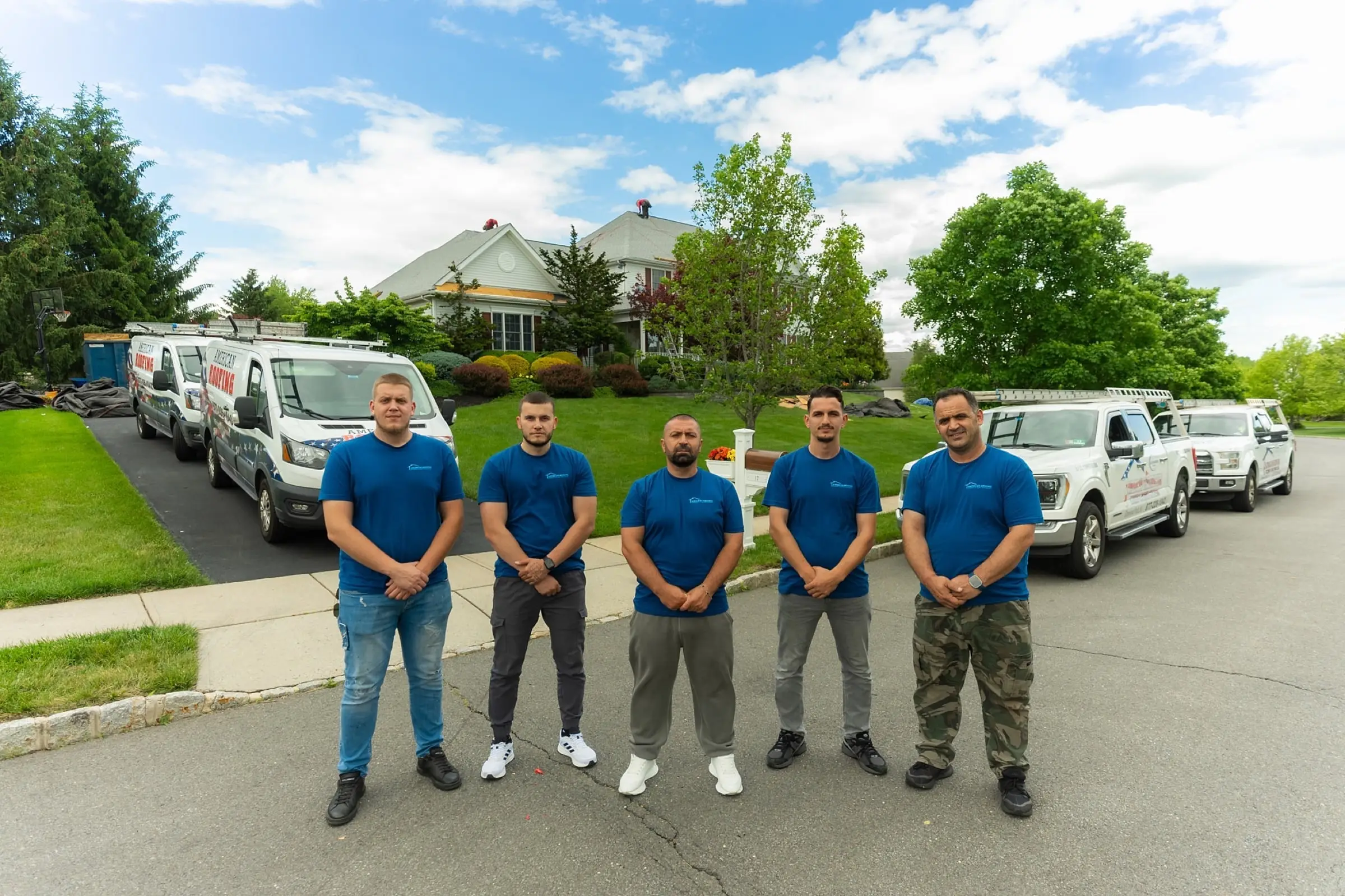 The American Roofing crew standing in front of the company vans and trucks
