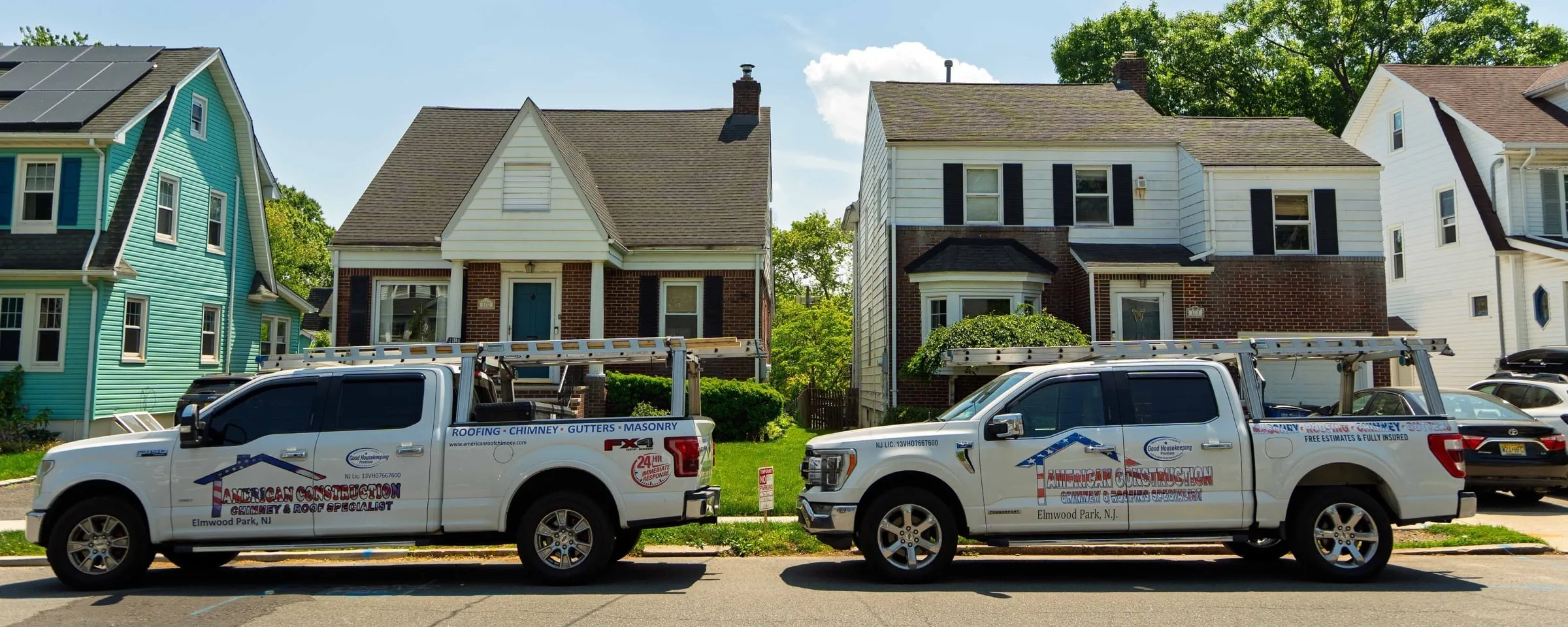 Two American Roofing pickup trucks with ladder racks parked on a New Jersey street